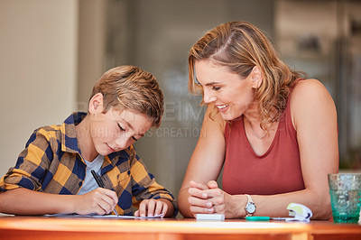 Buy stock photo Shot of a young woman helping her son with his homework at home