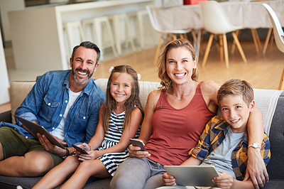 Buy stock photo Shot of a happy young family using wireless devices on the sofa at home