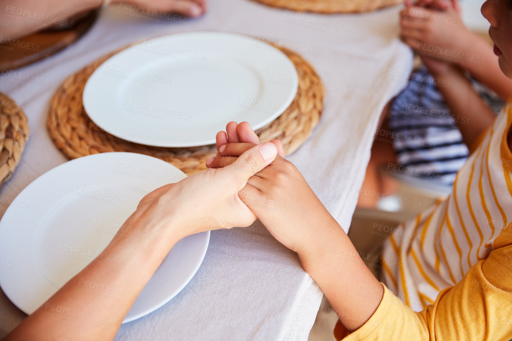 Buy stock photo Cropped shot of a family holding hands in prayer before having a meal together