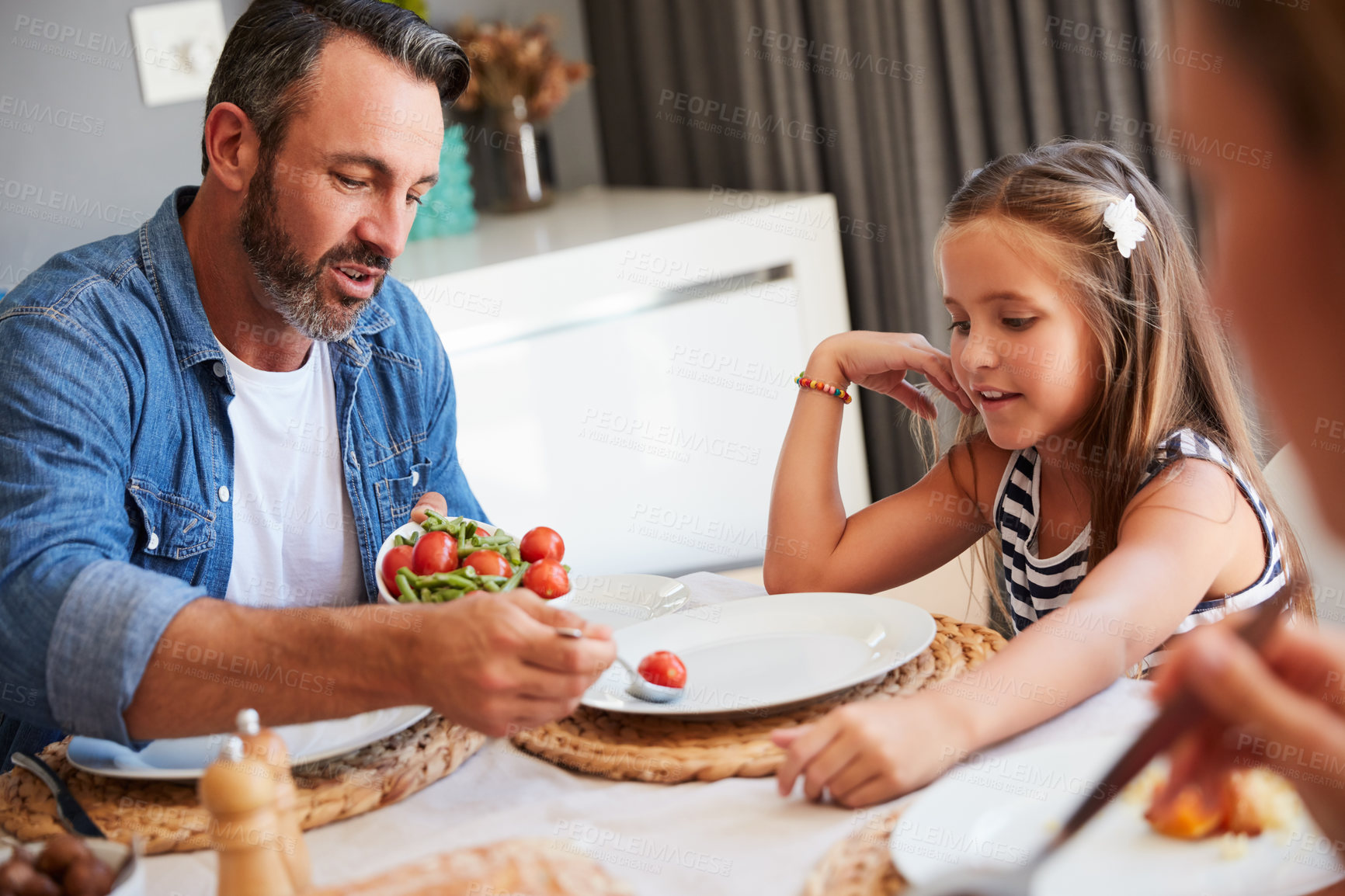 Buy stock photo Shot of a young family holding hands in prayer before having a meal together at home