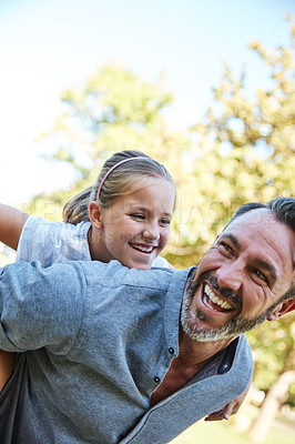 Buy stock photo Shot of an adorable little girl enjoying a piggyback ride with her father in the park