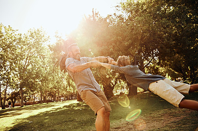 Buy stock photo Shot of an adorable little boy being swung around by his father in the park