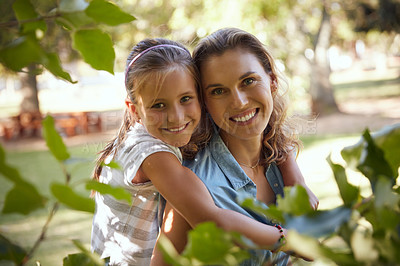Buy stock photo Shot of an adorable little girl enjoying a piggyback ride with her mother in the park