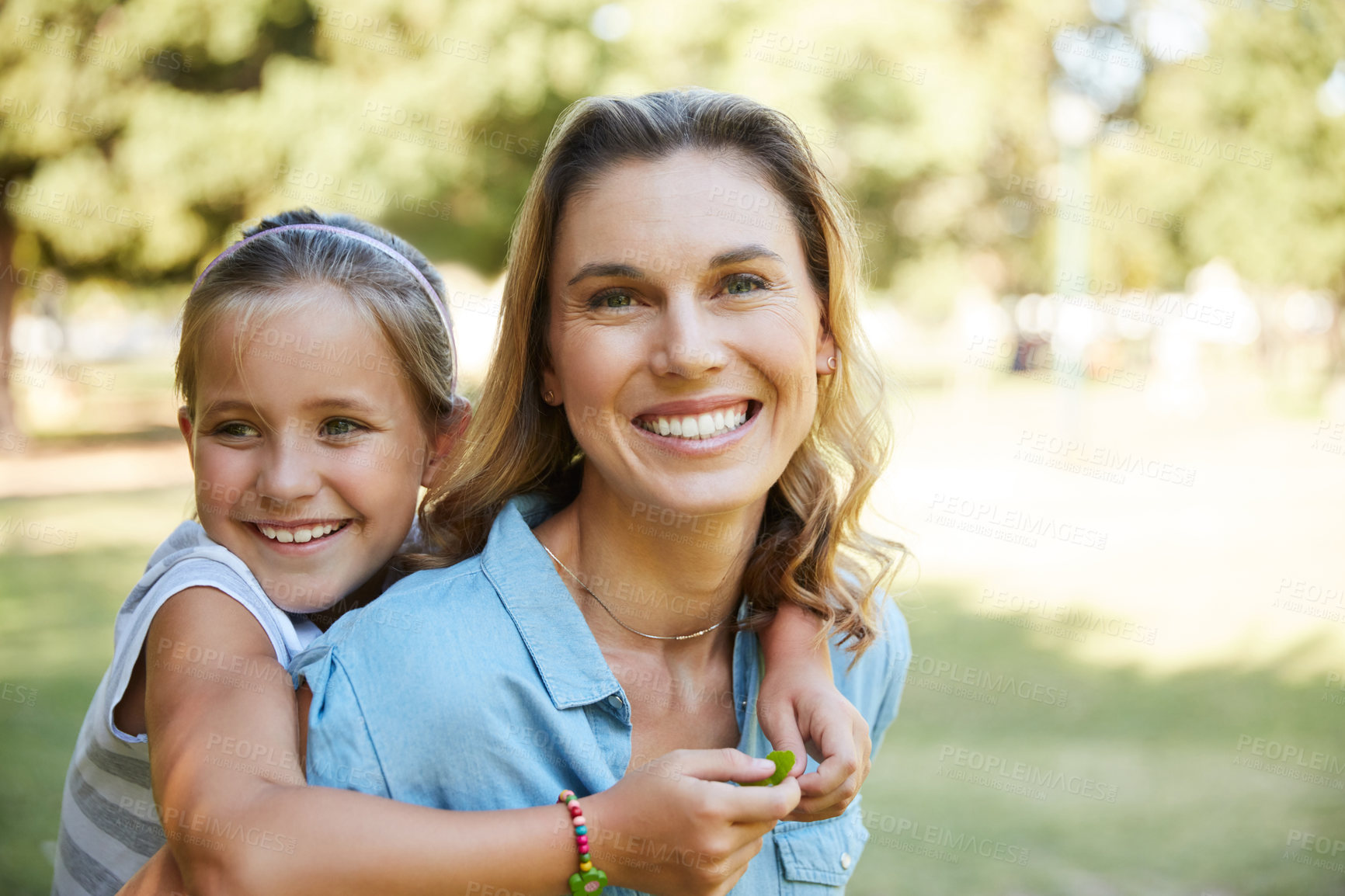 Buy stock photo Shot of an adorable little girl enjoying a piggyback ride with her mother in the park