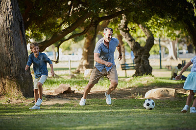 Buy stock photo Shot of an adorable little boy playing soccer with his father in the park