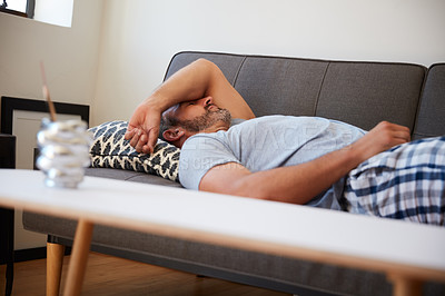 Buy stock photo Cropped shot of a mature man looking exhausted while lying on a couch at home in the morning