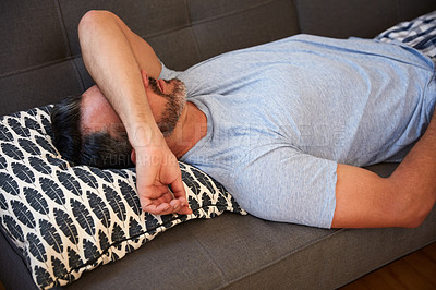 Buy stock photo High angle shot of a mature man looking exhausted while lying on a couch at home in the morning