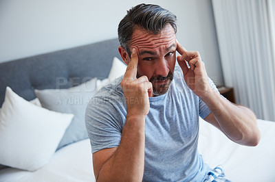 Buy stock photo Cropped shot of an attractive mature man suffering from a headache in his bedroom in the morning
