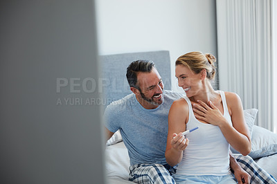 Buy stock photo Cropped shot of a middle aged couple looking happy after taking a home pregnancy test in their bedroom