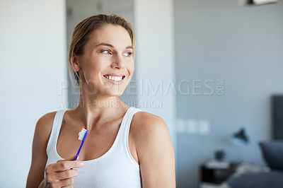 Buy stock photo Cropped shot of an attractive young woman looking away while holding a toothbrush at home