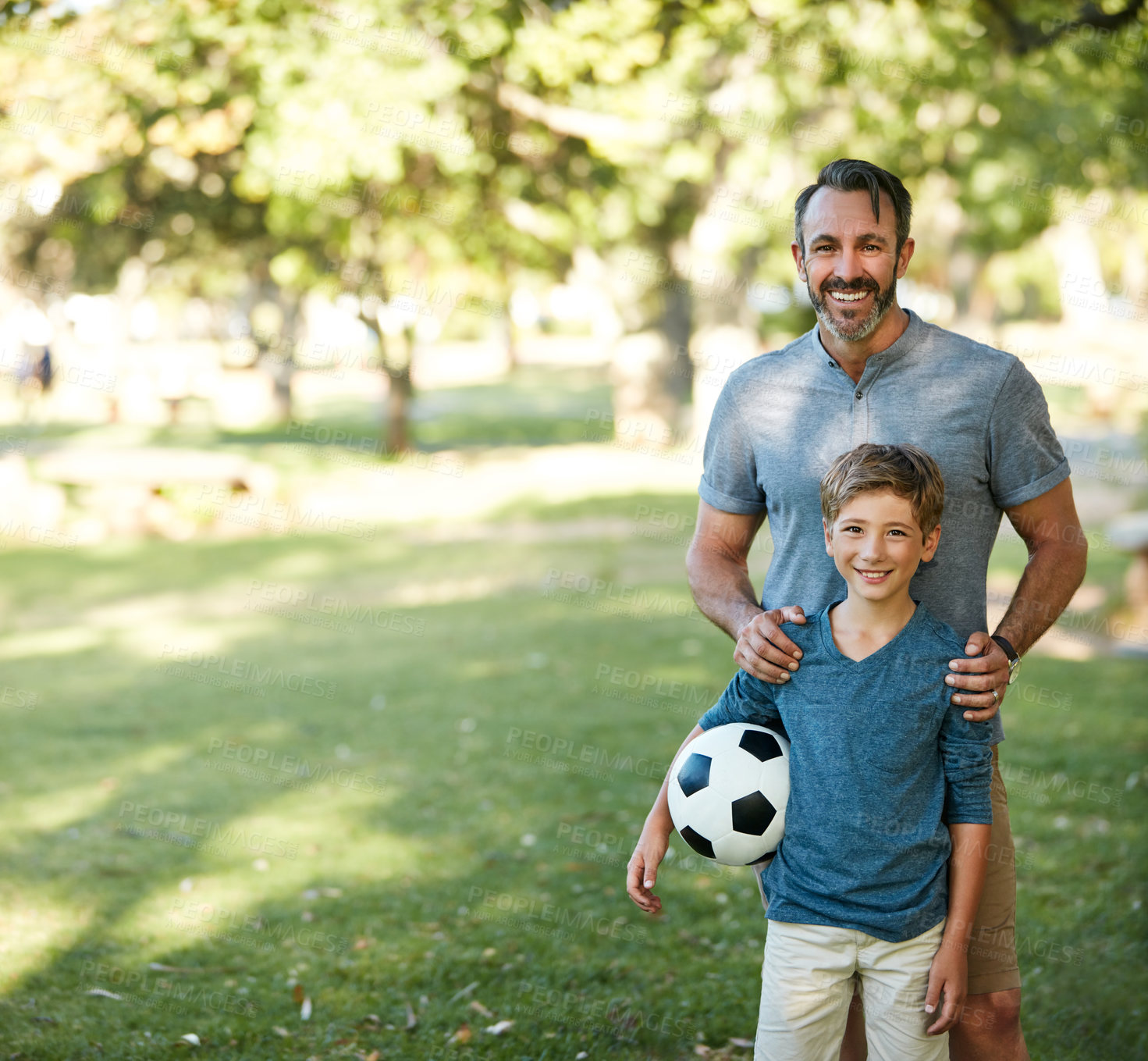 Buy stock photo Shot of an adorable little boy playing soccer with his father in the park