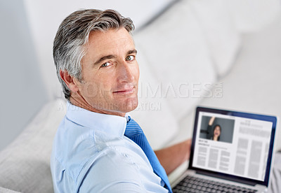 Buy stock photo Portrait of a confident mature businessman and sitting on a sofa while working on his laptop indoors