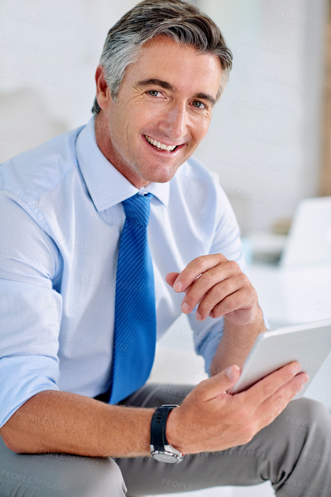 Buy stock photo Portrait of a confident mature businessman sitting on a sofa indoors while working on a tablet