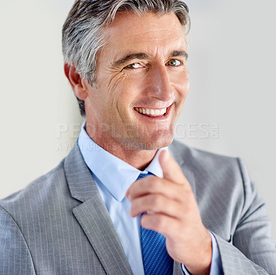 Buy stock photo Portrait of a confident mature businessman wearing a suit and standing indoors while pointing at the camera