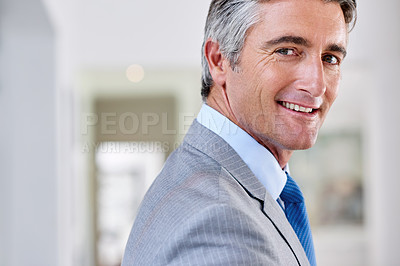 Buy stock photo Headshot of a confident mature businessman smiling over his shoulder and wearing a suit indoors