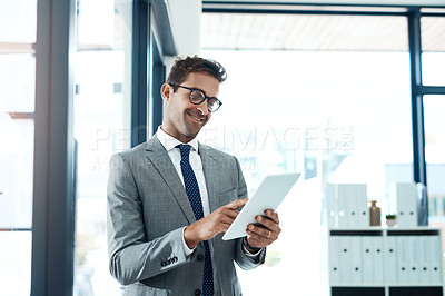 Buy stock photo Shot of a professional businessman using a digital tablet in his office