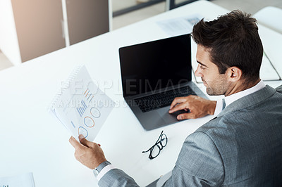 Buy stock photo Rearview shot of a businessman looking at a document at his desk