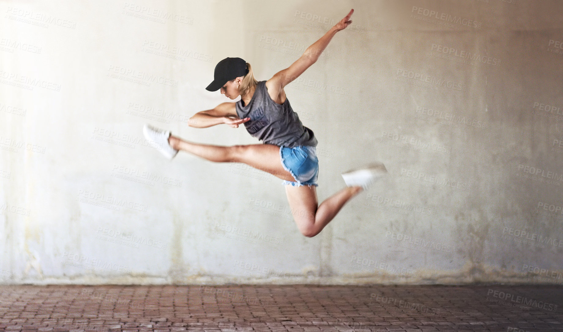 Buy stock photo Woman, dancing and jump with city wall background or creative workout for hip hop, urban or fitness. Female person, split and artistic practice or healthy movement with strength, street or outdoor