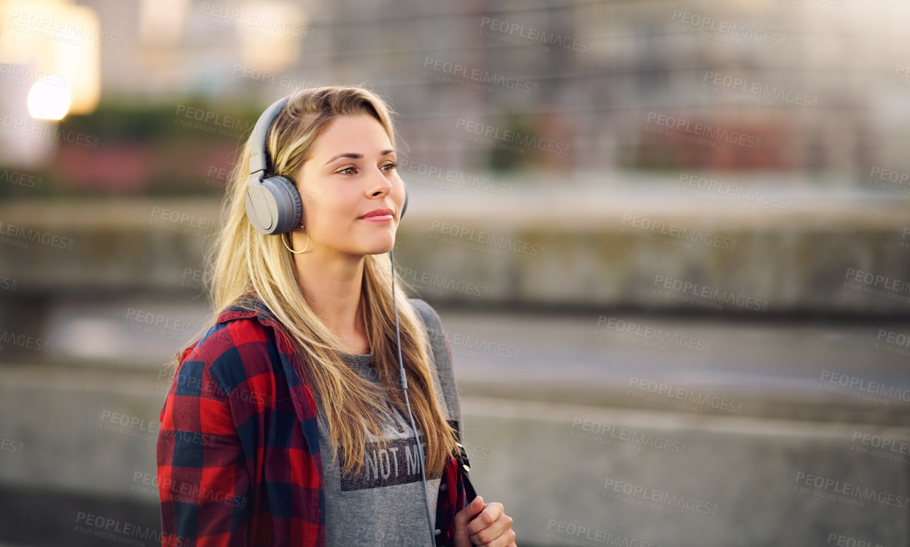 Buy stock photo Cropped shot of an attractive young woman walking down the street and listening to music through her headphones