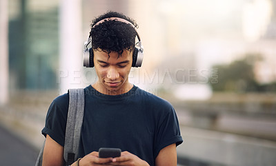 Buy stock photo Phone, music and headphones with a man in the city, streaming an audio subscription service outdoor. Mobile, social media and backpack with a young male tourist outside in an urban town for travel