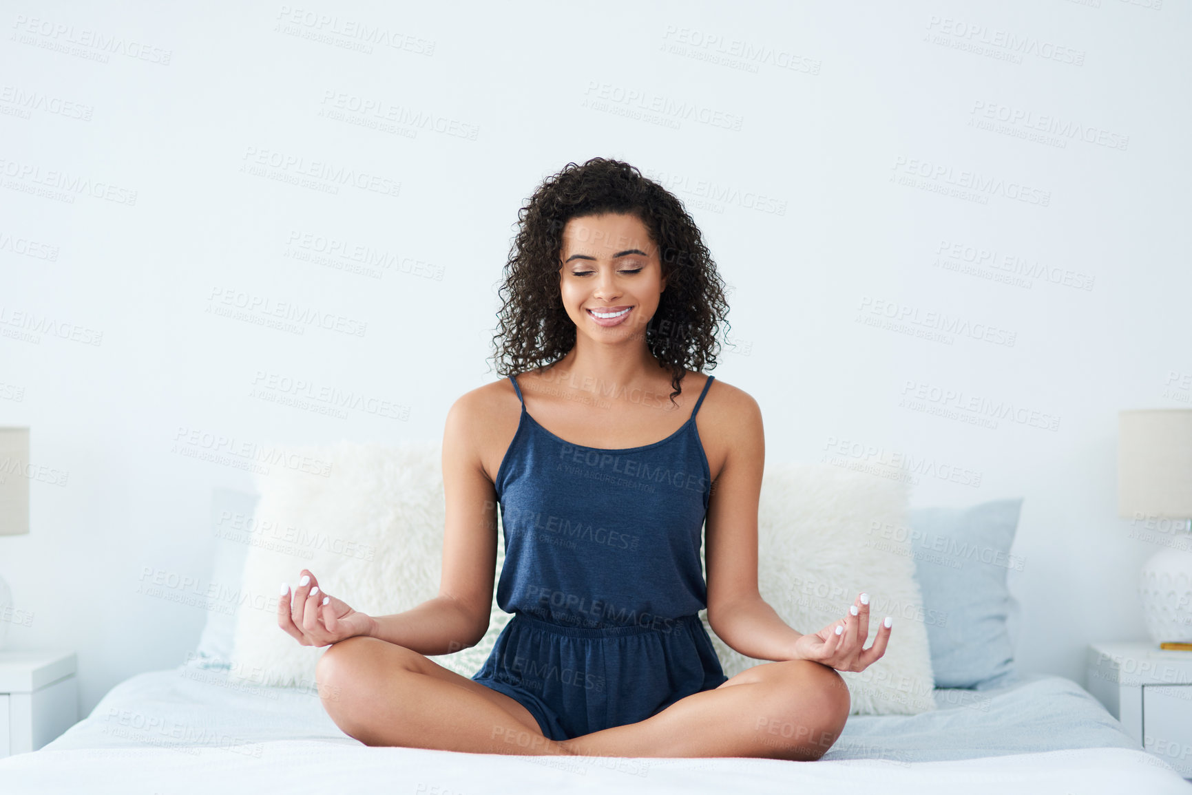 Buy stock photo Shot of an attractive young woman sitting and meditating on her bed in the morning