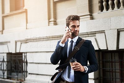 Buy stock photo Shot of a handsome young businessman talking on his cellphone while heading to work in the morning