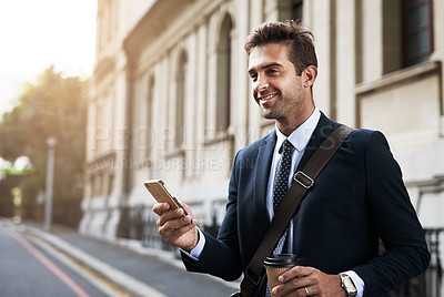 Buy stock photo Shot of a handsome young businessman texting on his cellphone while heading to work in the morning