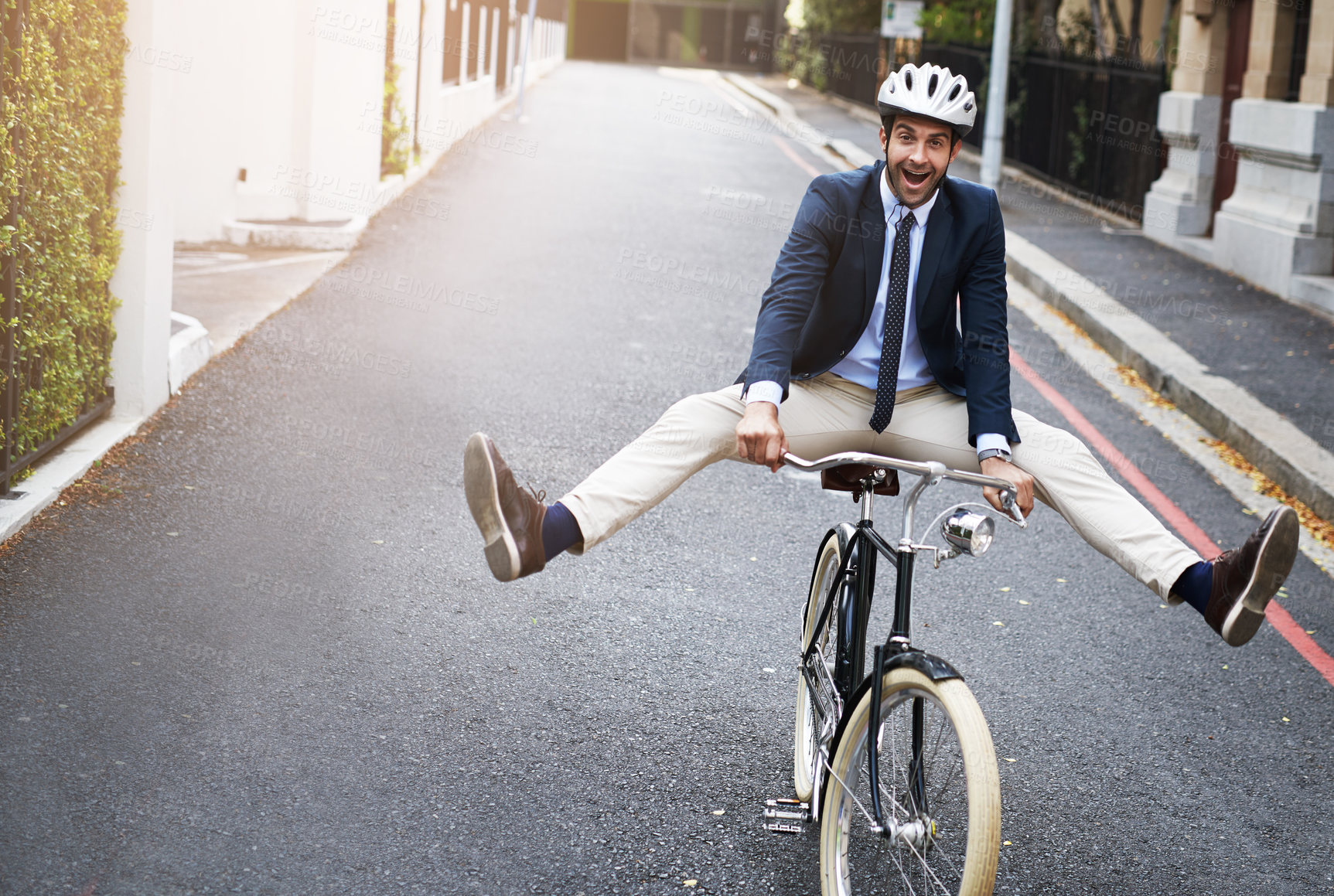 Buy stock photo Shot of a handsome young businessman riding his bicycle to work in the morning