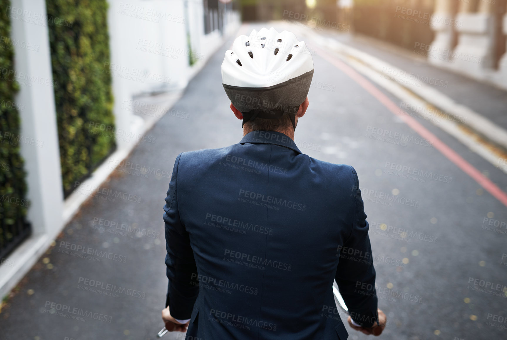 Buy stock photo Rearview shot of a handsome young businessman riding his bicycle to work in the morning