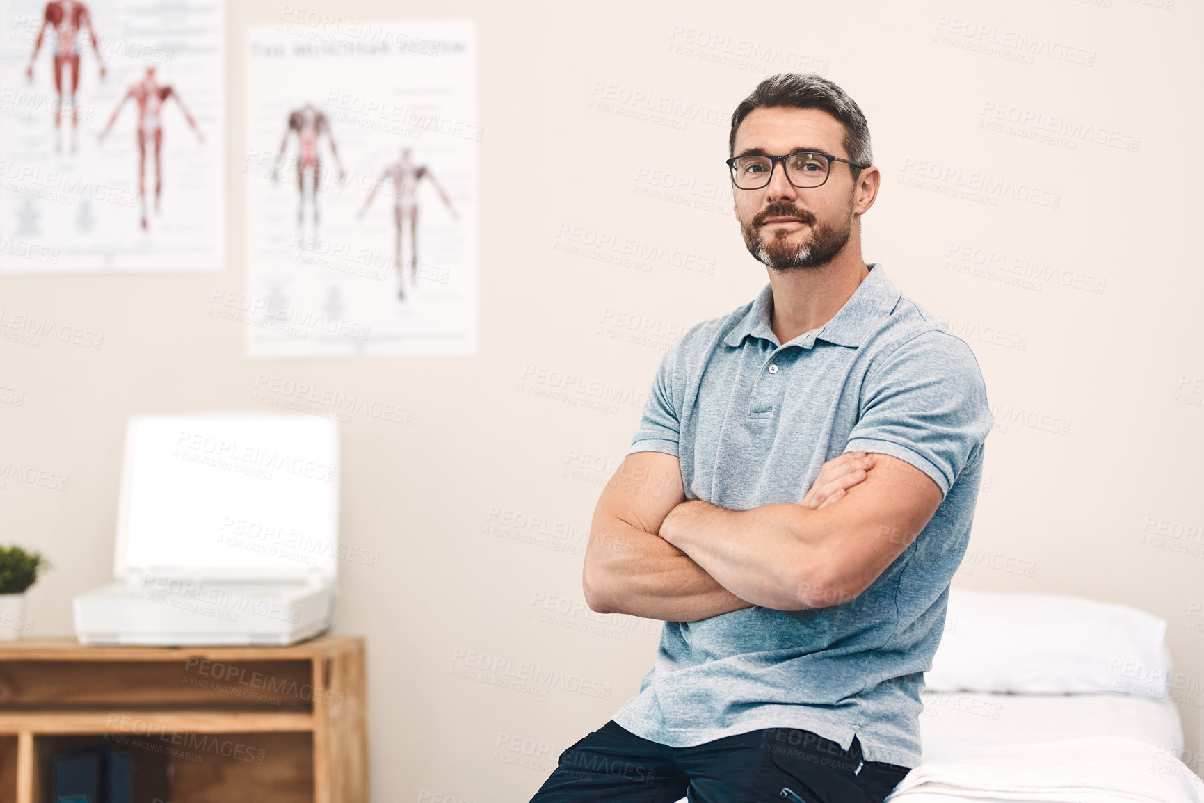 Buy stock photo Portrait of a handsome mature male physiotherapist posing with his arms folded in his office