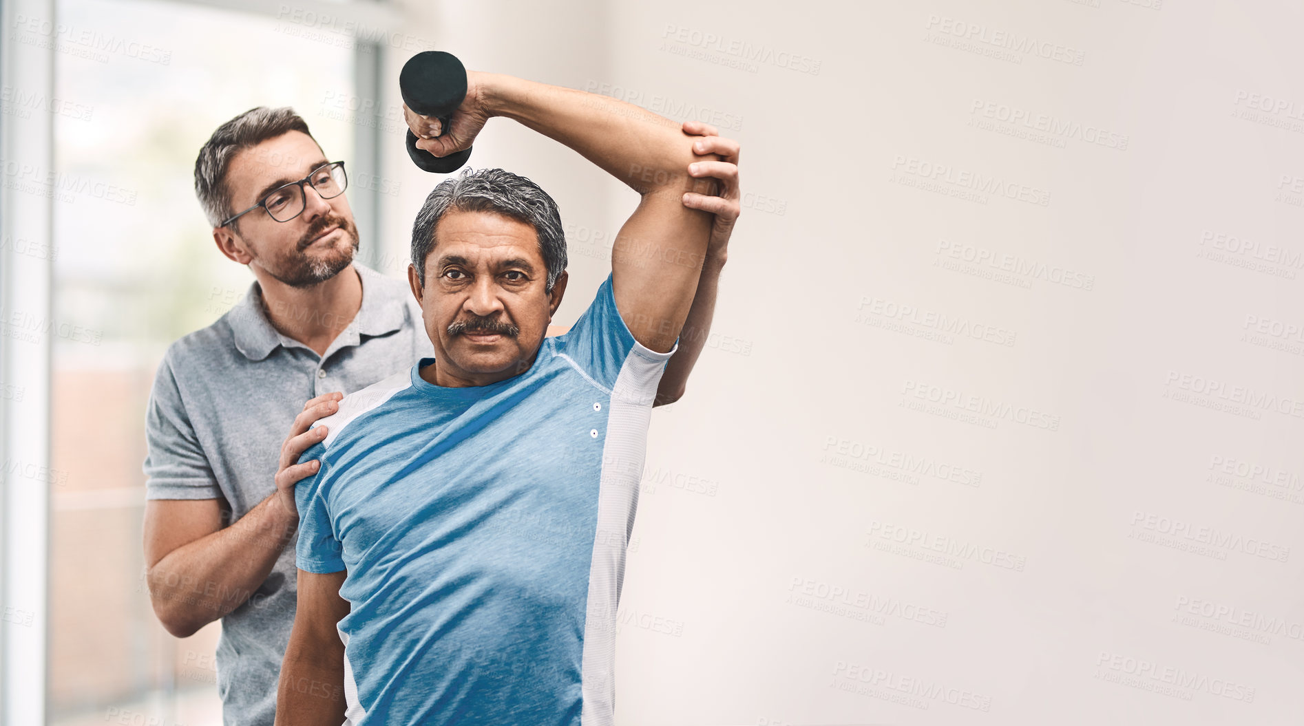 Buy stock photo Shot of a senior man exercising with dumbbells during a rehabilitation session with his physiotherapist