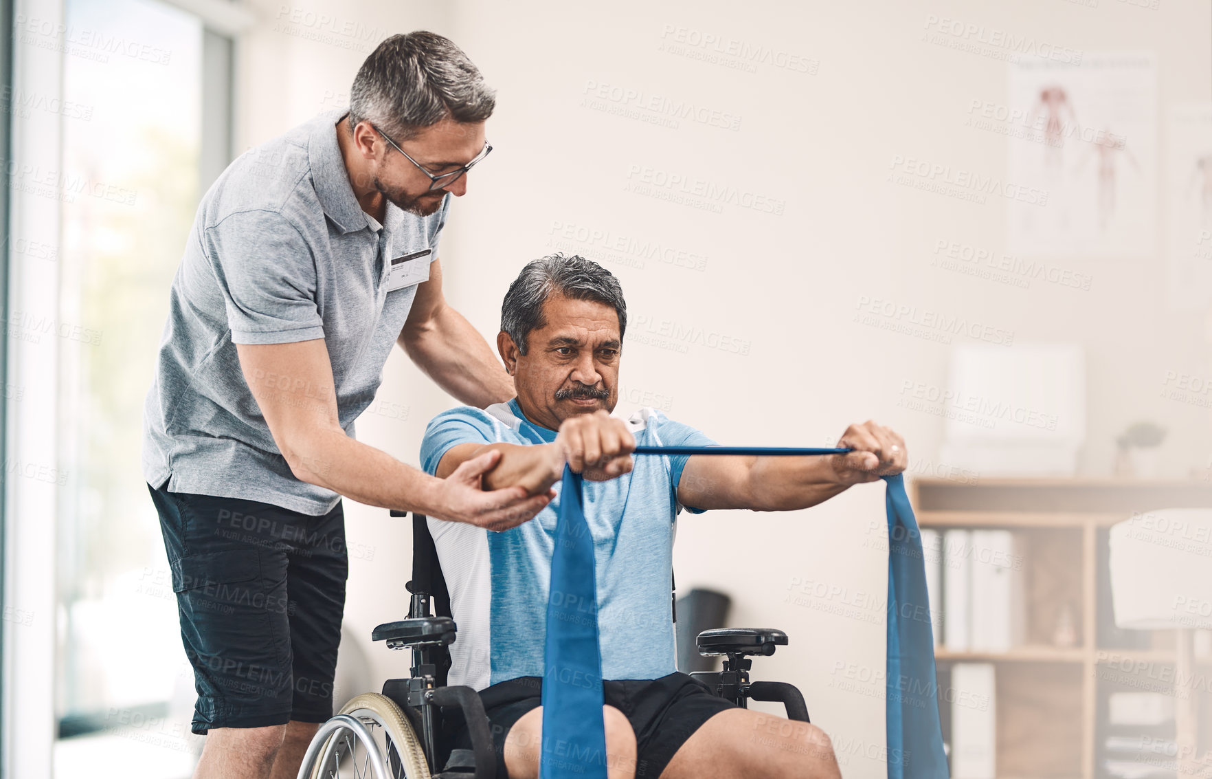 Buy stock photo Shot of a senior man in a wheelchair exercising with a resistance band along side his physiotherapist