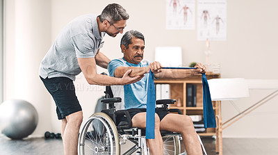 Buy stock photo Shot of a senior man in a wheelchair exercising with a resistance band along side his physiotherapist