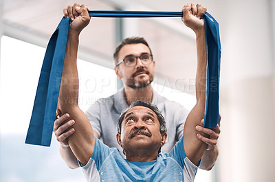 Buy stock photo Shot of a senior man exercising with a resistance band during a rehabilitation session with his physiotherapist