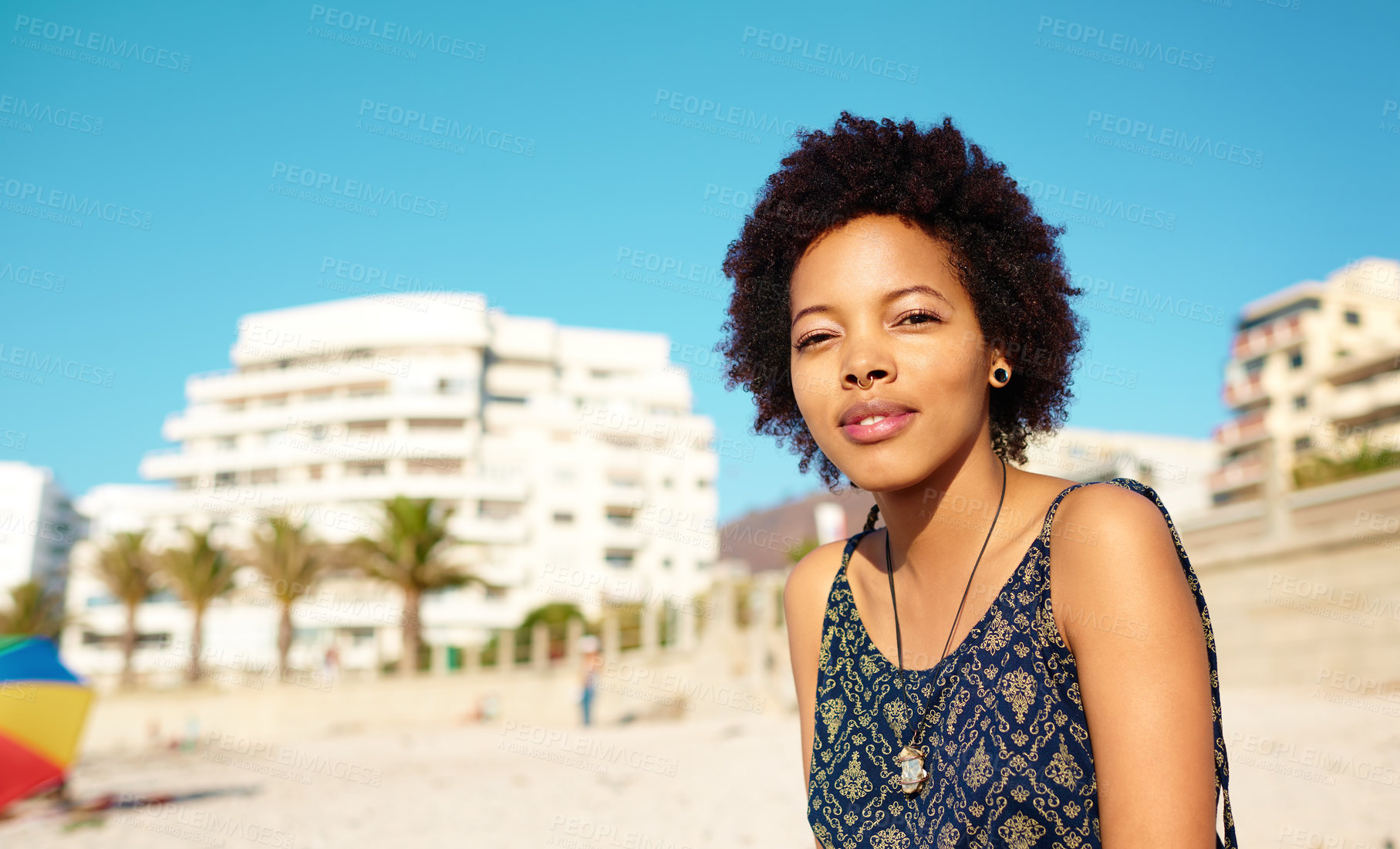 Buy stock photo Portrait of an attractive young woman wearing casual clothes while sitting on the beach alone and enjoying the sunshine