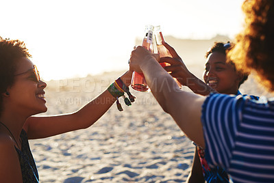 Buy stock photo Shot of an attractive young trio of women celebrating and having a drink together on the beach during the day