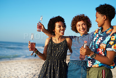 Buy stock photo Shot of three attractive young women standing and holding each other on the beach during the day