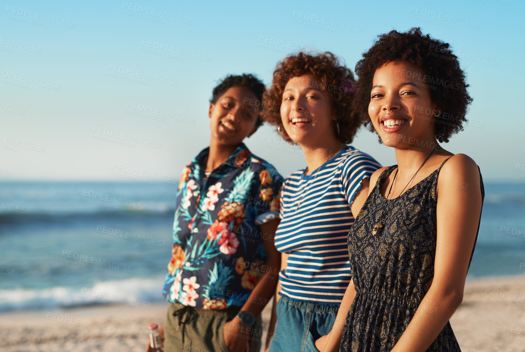 Buy stock photo Portrait of three attractive young women standing together and posing on the beach during the day