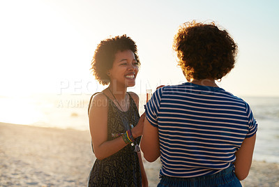 Buy stock photo Cropped shot of two attractive young women standing on the beach and enjoying a drink together during the day