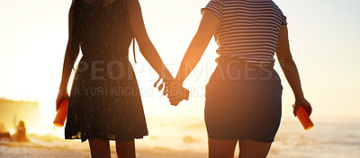 Buy stock photo Rearview shot of two unrecognizable young women holding hands on the beach at sunset