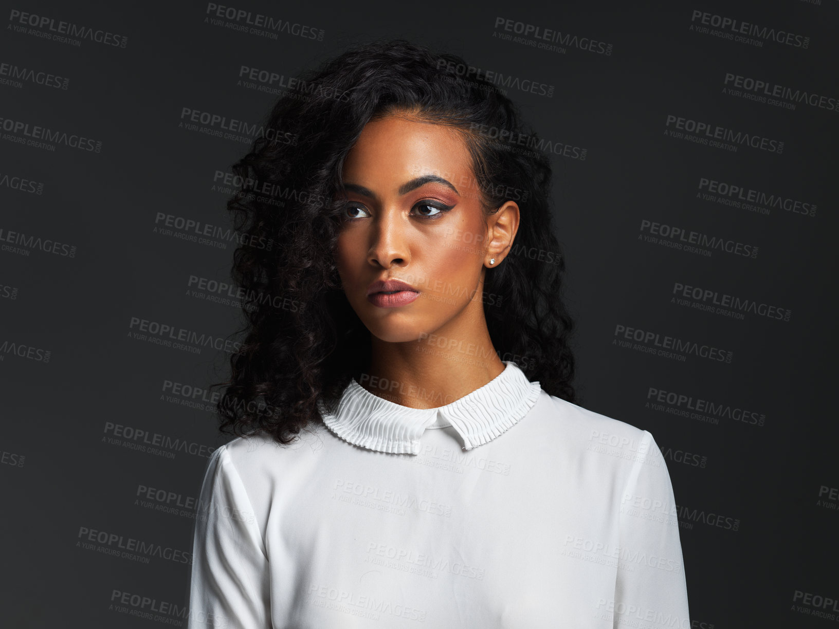 Buy stock photo Studio shot of an attractive young woman wearing a white blouse and posing alone against a dark background