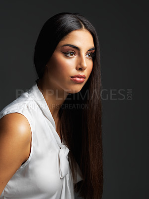 Buy stock photo Studio shot of an attractive young woman wearing a white blouse and posing against a dark background