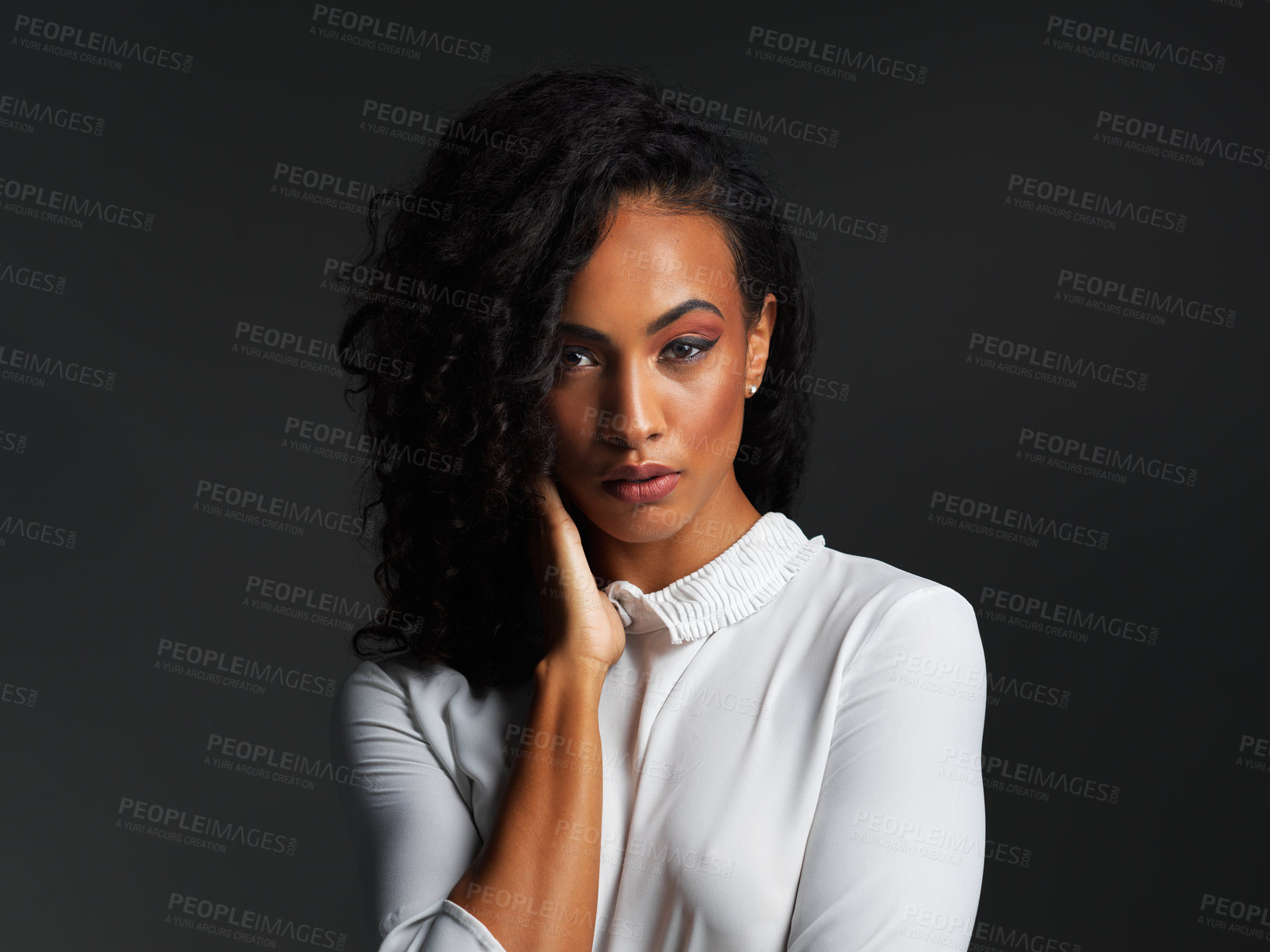Buy stock photo Portrait of an attractive young woman wearing a white blouse and posing alone against a dark background in the studio
