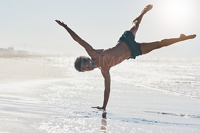 Buy stock photo Full length shot of a handsome young man balancing on his hand while dancing on the beach during the day