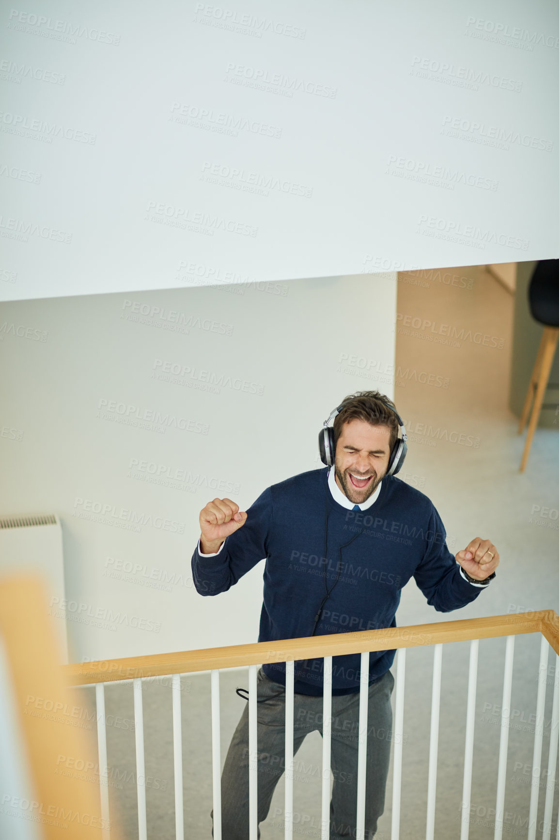 Buy stock photo Shot of a young businessman listening to music in an office