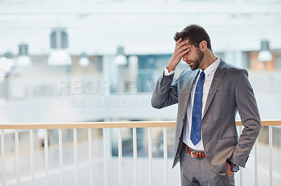 Buy stock photo Shot of a young businessman looking stressed out while standing in an office