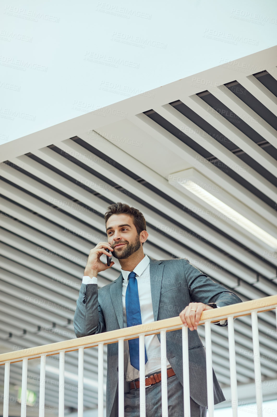 Buy stock photo Shot of a young businessman talking on a cellphone in an office