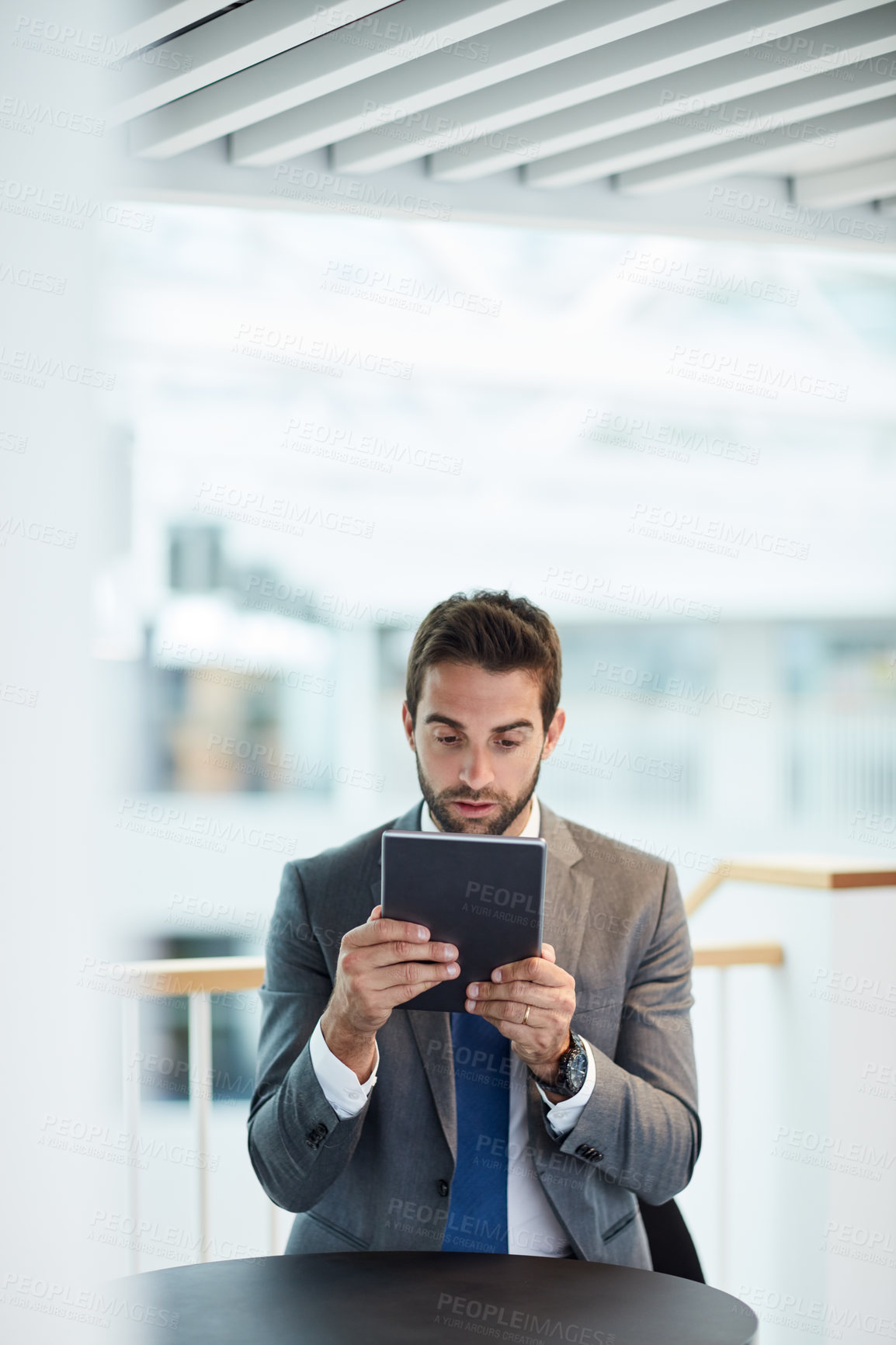 Buy stock photo Shot of a young businessman looking shocked while using a digital tablet in an office