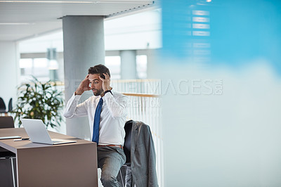 Buy stock photo Shot of a young businessman looking shocked while working on a laptop in an office
