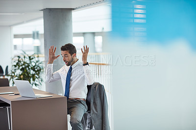 Buy stock photo Shot of a young businessman looking shocked while working on a laptop in an office